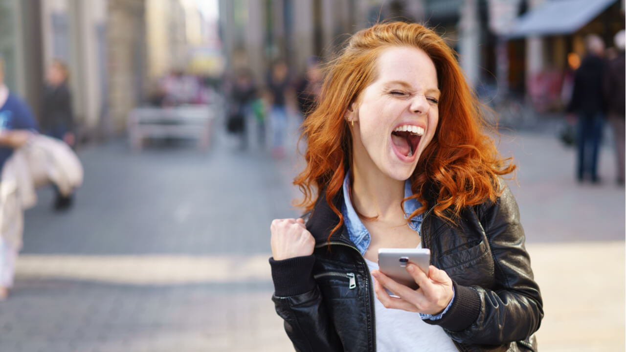 young woman excited to read content on mobile phone | content customers love