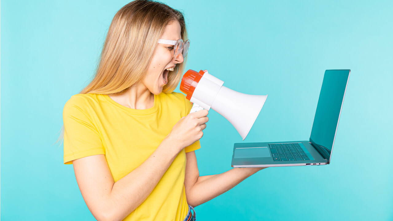 Young woman with laptop and megaphone | marketing your small business without a budget