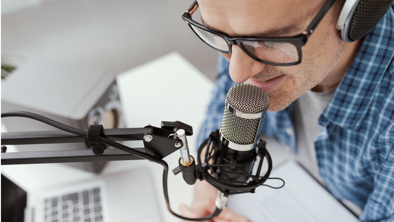 closeup of a man with a microphone and laptop appearing as a guest on a podcast