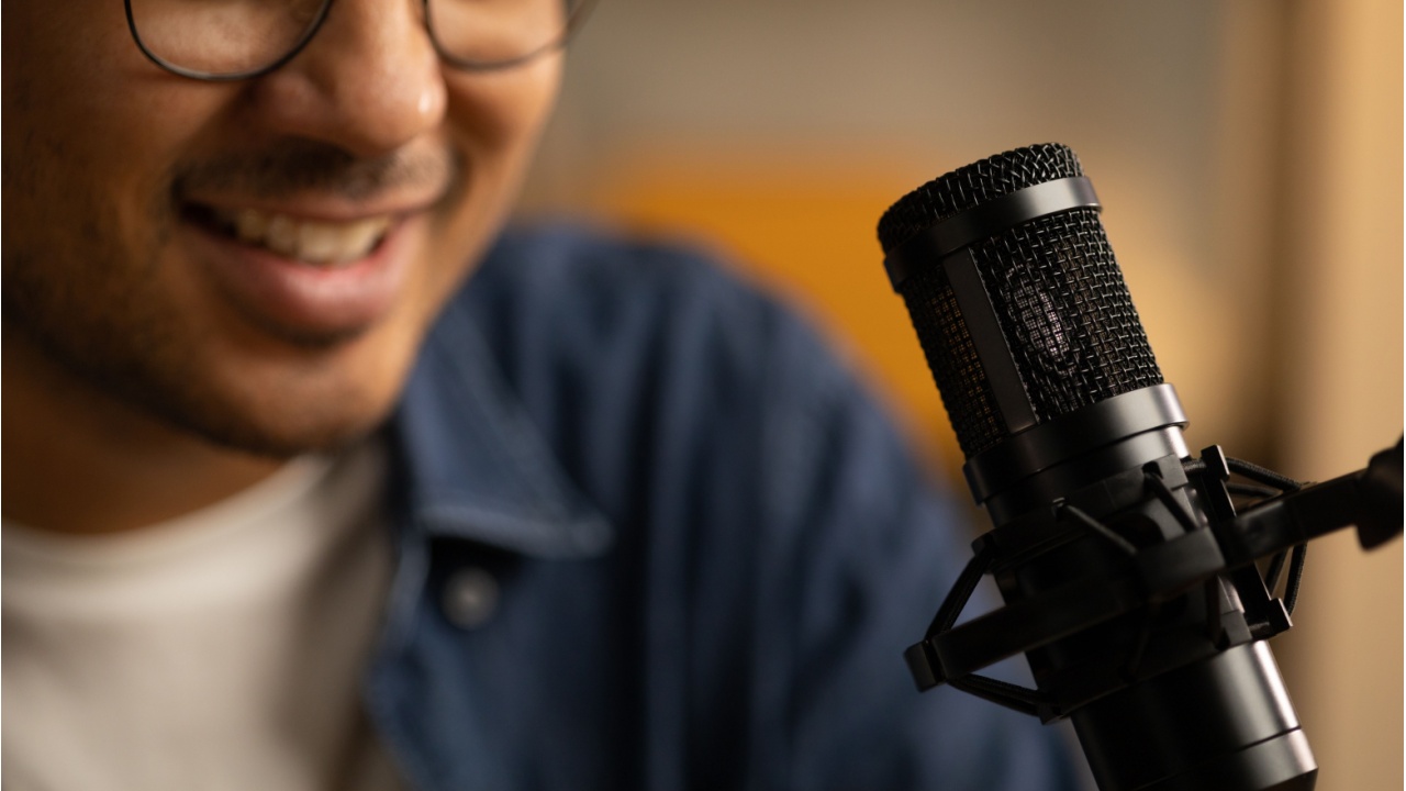 closeup of a man talking into a podcast microphone | How to Find the Best Podcasts to Help Grow Your Business